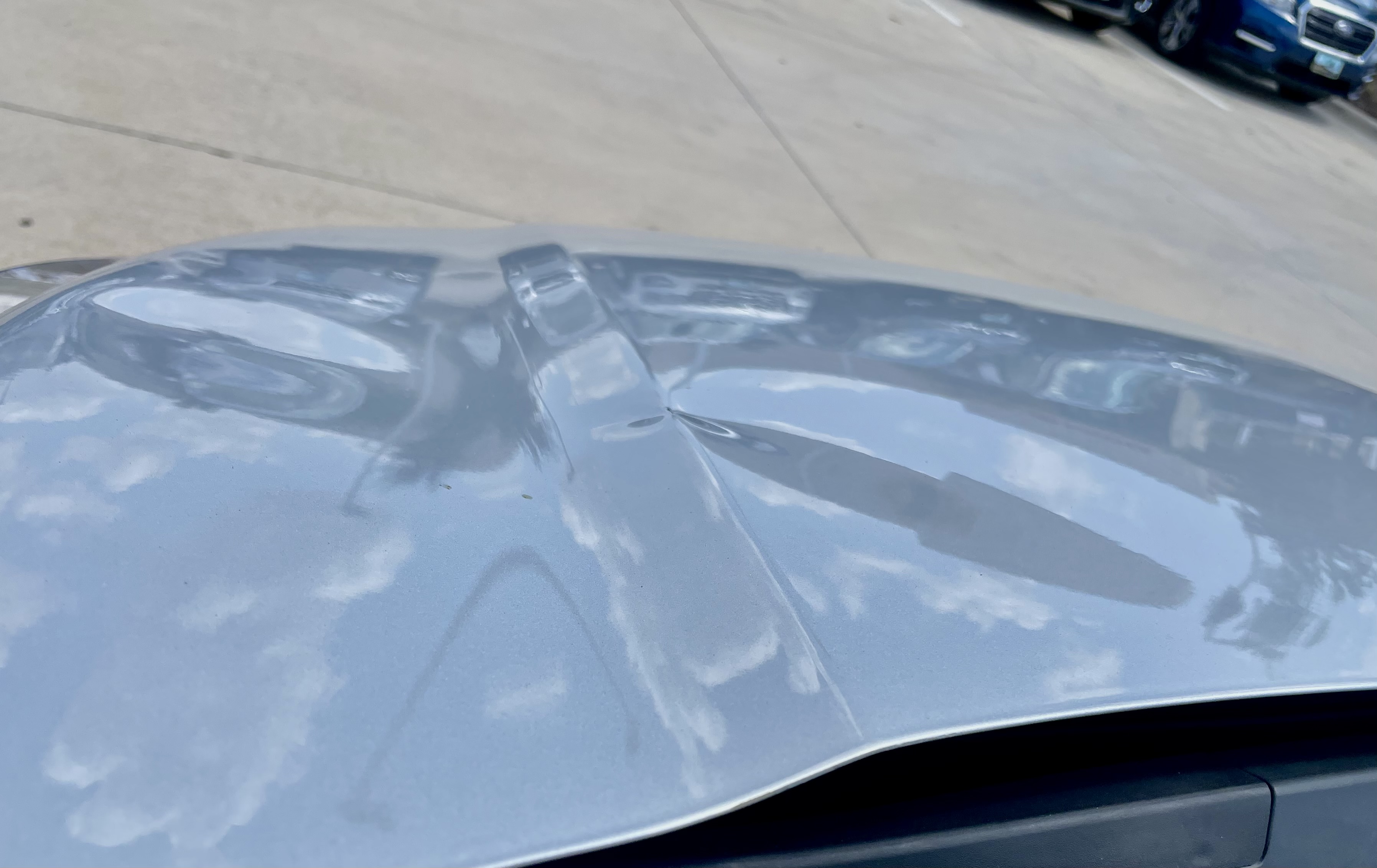 Before PDR — silver sedan hood with large dent